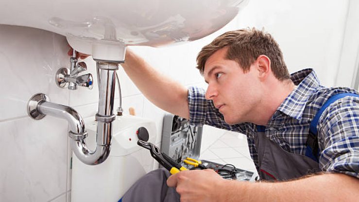 Portrait of male plumber fixing a sink in bathroom